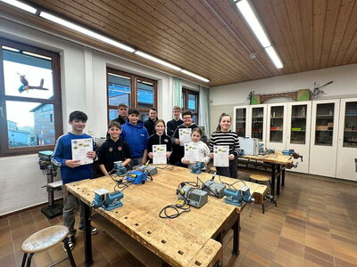 Gruppenfoto der Teilnehmer, hinter einer Werkbank stehend