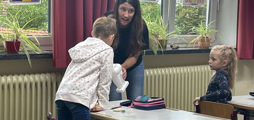 Frau Riedl mit einem Zahnmodell bei einem Schüler
