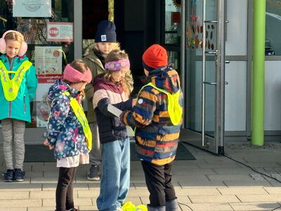 Schüler mit Leuchtwesten vor dem Schuleingang