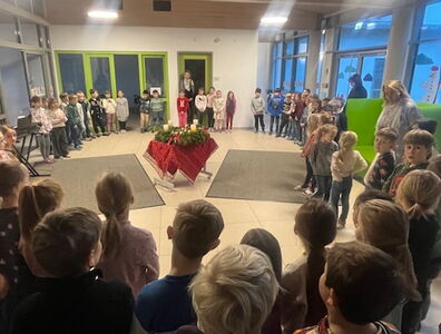 Die Schulfamilie steht im Kreis um den Adventskranz in der Aula