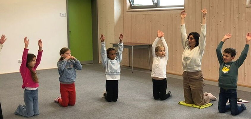 Kinder mit Frau Turhan bei einer Yogaübung
