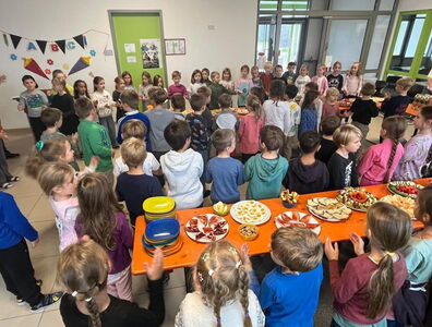 Viele Schulkinder stehen klatschend am Frühstücksbuffet