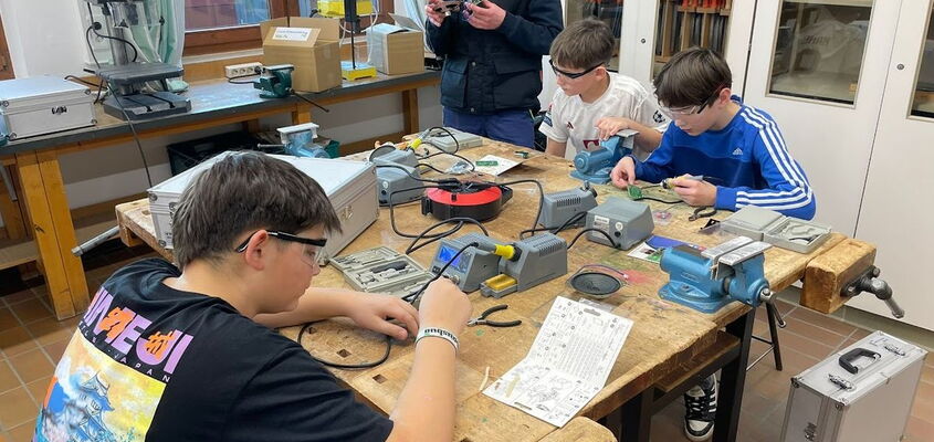 Schüler tüfteln gemeinsam auf einer Werkbank