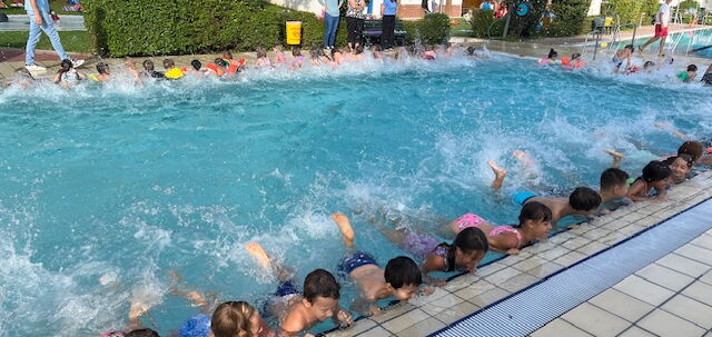 Grundschüler führen entlang des Beckenrandes Beinübungen durch