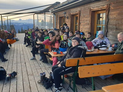 Gruppenbild Schüler sitzen vor einer Skihütte