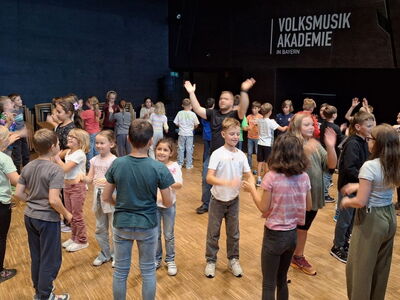 Die Klassen 4a und 4b klatschend in einem Raum der Volksmusik Akademie