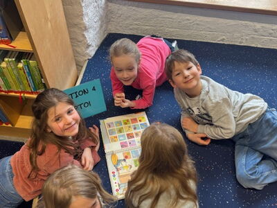 Die Schulkinder liegen gemütlich mit einem Buch am Boden