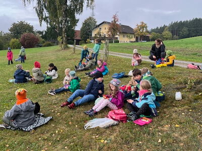 Die Schulkinder sitzen auf einer Wiese und machen eine Pause