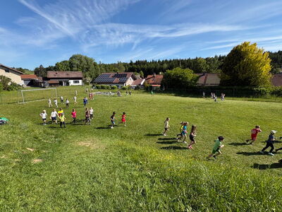 Schulkinder joggen über einen Fußballrasen