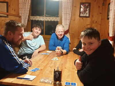 Schüler und Lehrer beim Karten spielen in einer Hütte