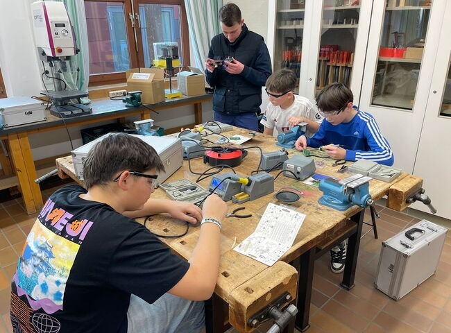 Schüler tüfteln gemeinsam auf einer Werkbank